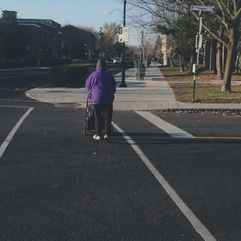 Personne aînée avec un panier roulant traversant à l'intersection
